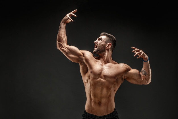 bodybuilder-posing-fitness-muscled-man-dark-wall_136403-1029